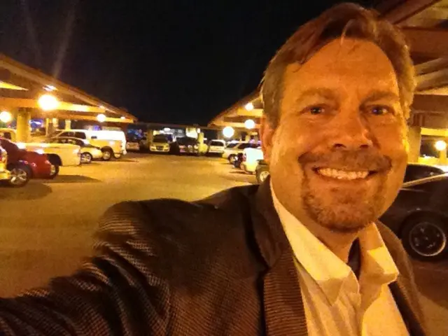 In this picture I can see a person with a smile. I can see the vehicles in the parking space. I can...