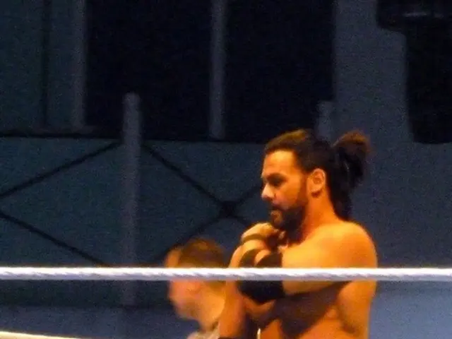 In this picture there are two men in the center of the image and there is a rope boundary in the...